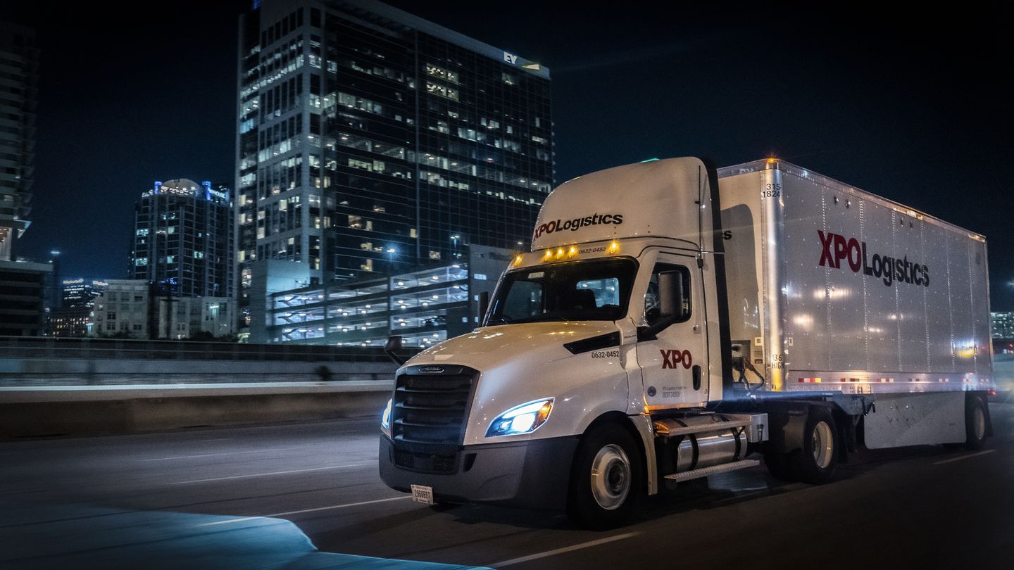 XPO truck driving down the highway at night