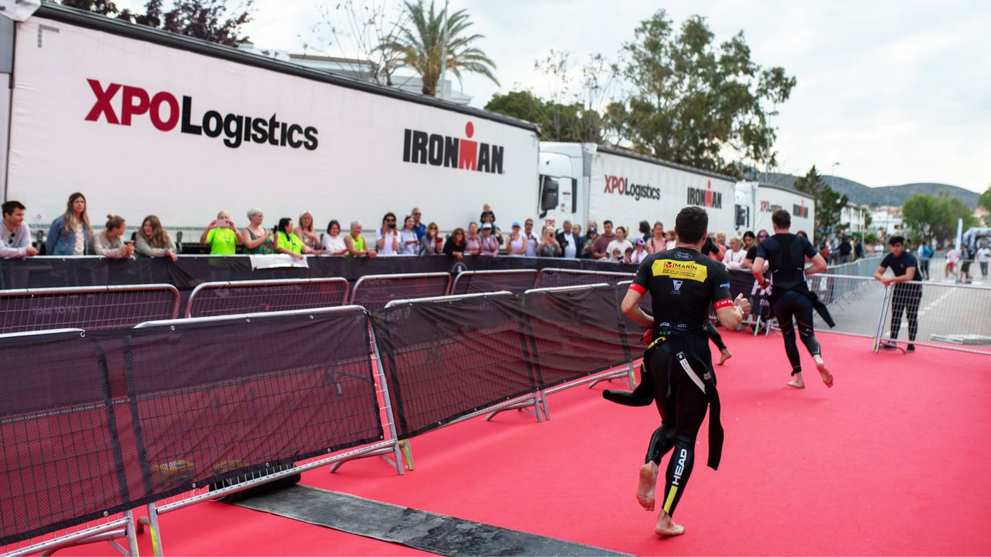 Man competing in IRONMAN competition with XPO trailers in background