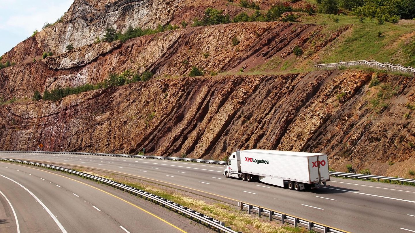 XPO truck driving down a highway with mountains