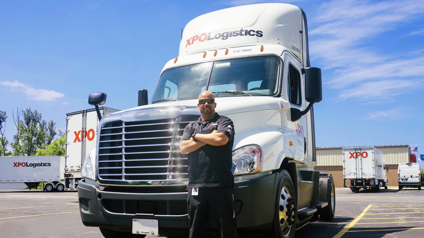 Un camionneur se tient devant un camion XPO