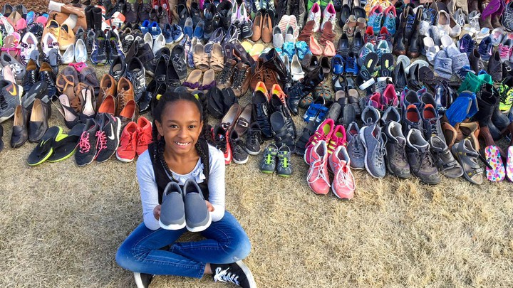 Child holds shoes donated to Soles4Souls
