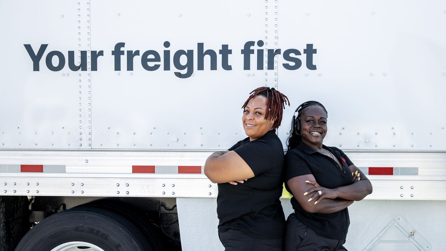 Two women posing with their arms crossed in front of a truck